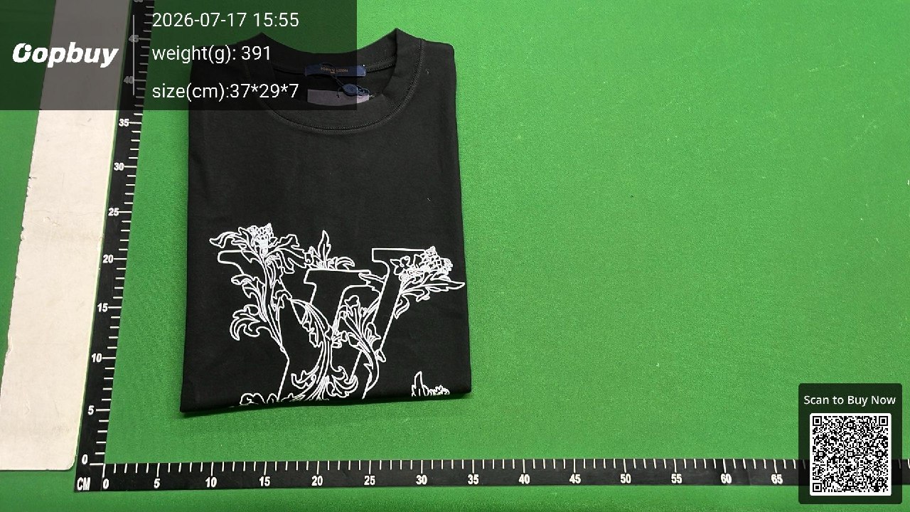 A folded dark T-shirt on a green warehouse ruler mat